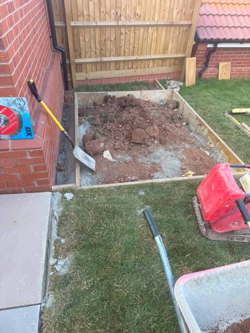 Groundworks in progress — excavated and shuttered patio base with wacker plate on site, ready for laying — Shrewsbury