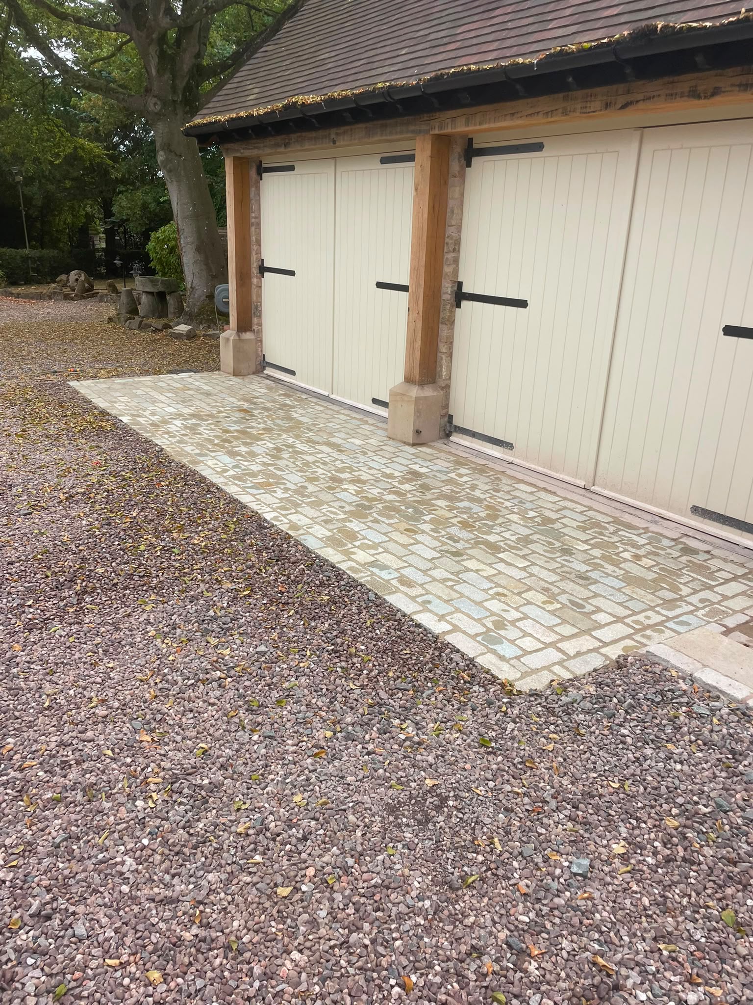 Granite sett apron laid in front of oak-framed garage doors with pink gravel surround — Shrewsbury