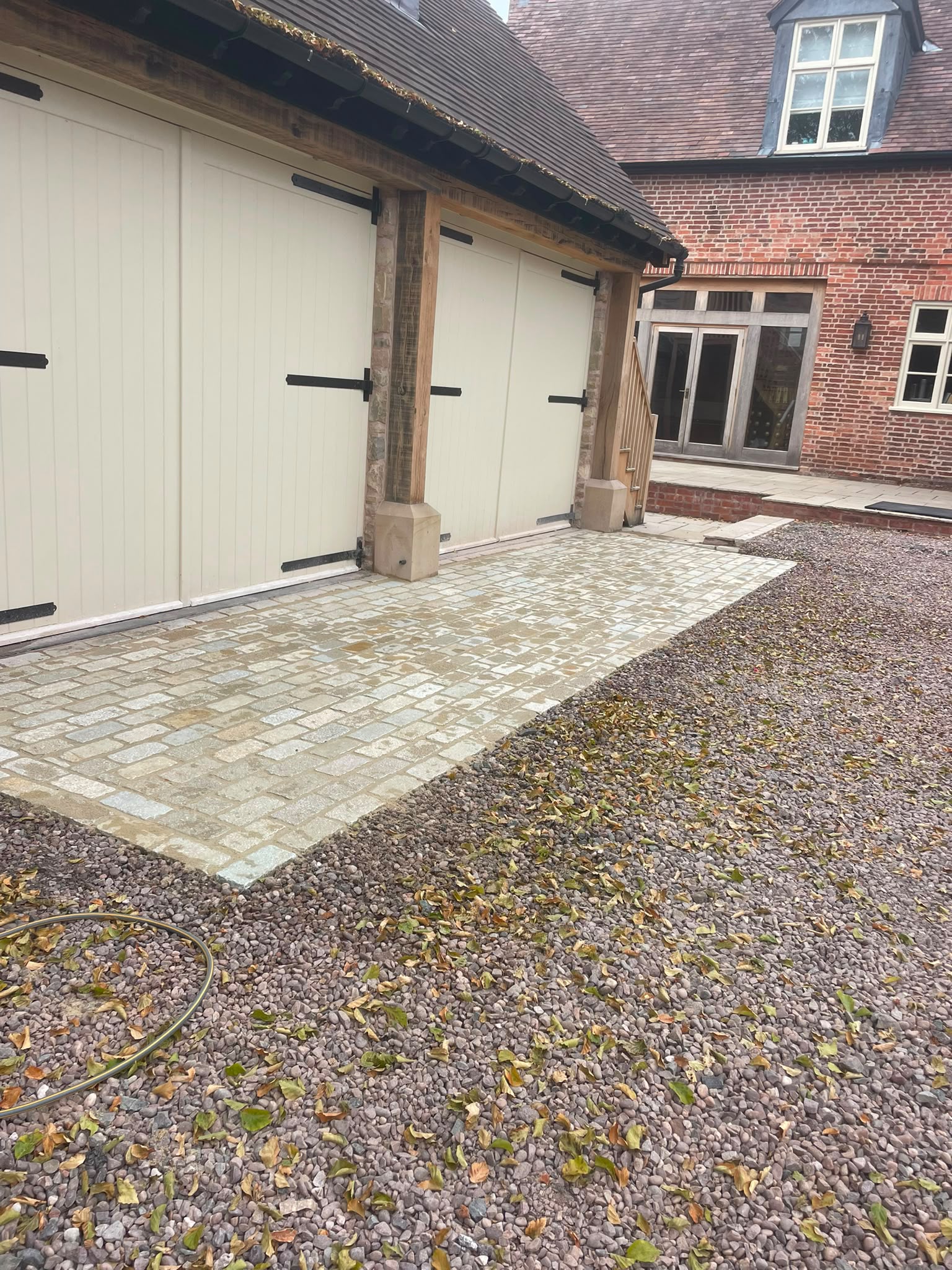 Granite sett courtyard hardstanding beside a brick barn conversion with gravel driveway — Shropshire
