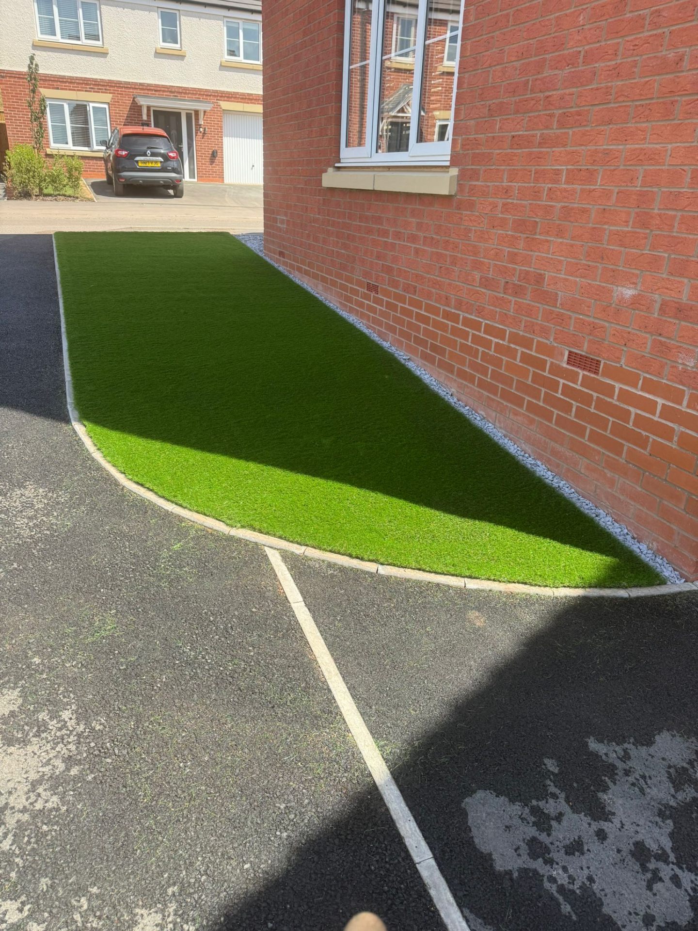 Artificial grass lawn with grey slate gravel border against brick wall — Shrewsbury front garden