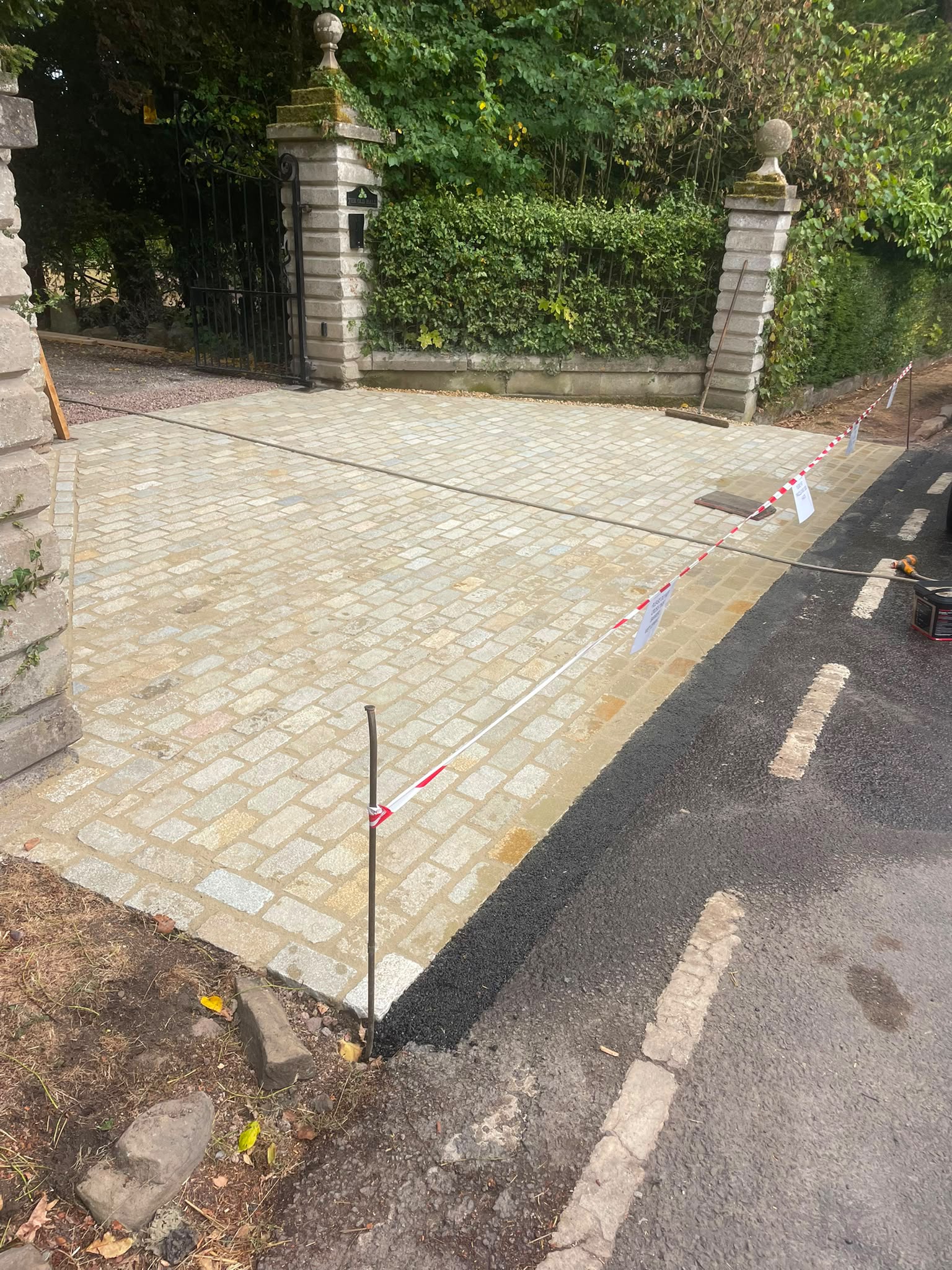 Reclaimed-style granite sett driveway entrance freshly laid and pointed at a gated country home
